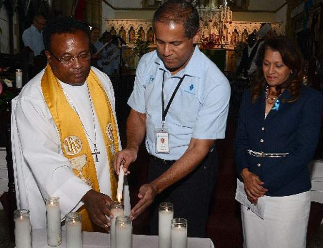 lights of the world: Interim rector Rev Carl Williams, left, and Nigel Baptiste, managing director, Republic Bank, light a candle during the bank’s interfaith service yesterday, at the Holy Trinity Cathedral, Port of Spain. Looking on is Anna-Maria Garcia Brooks, general manager, Group Human Resources. —Photo: ISHMAEL SALANDY
