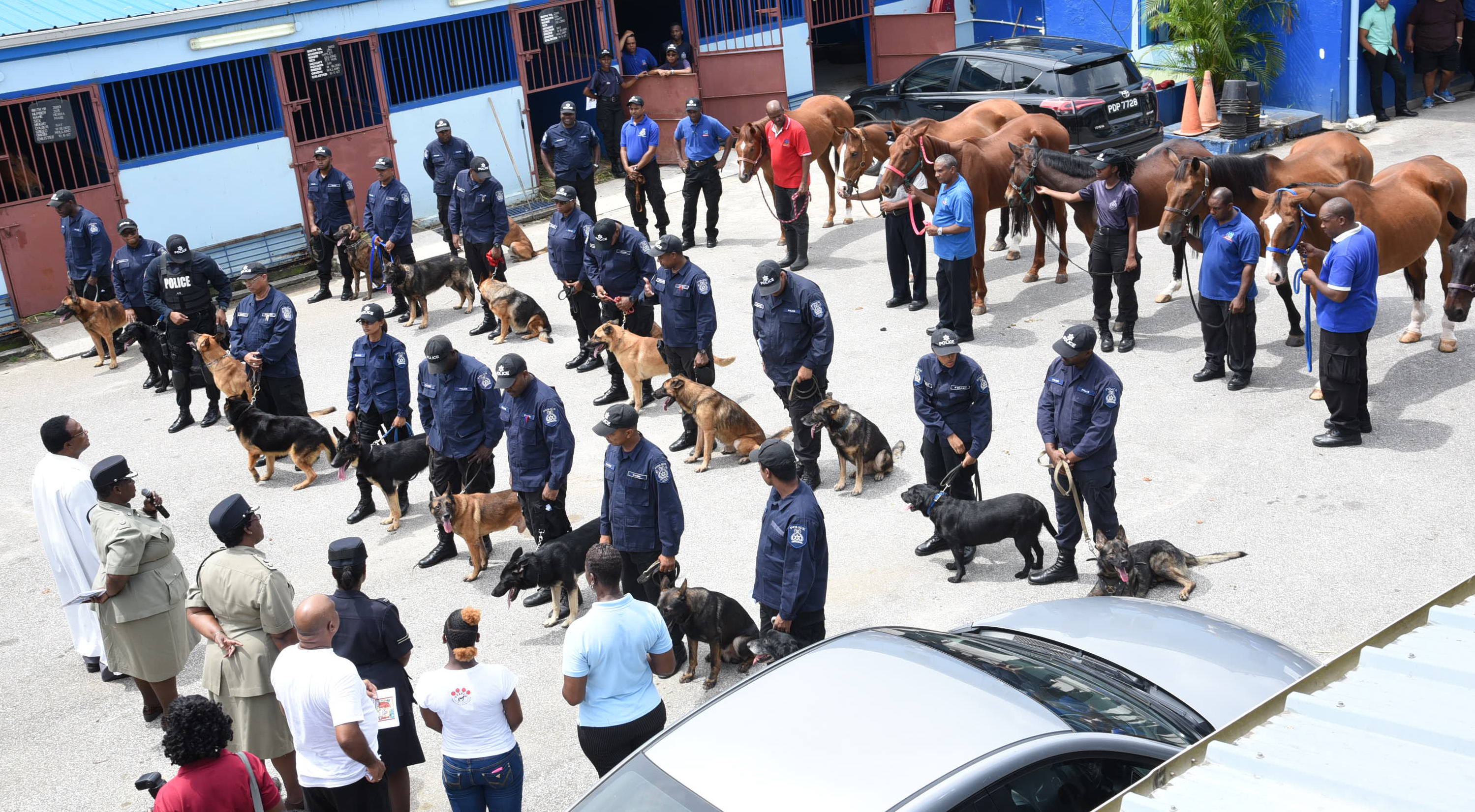 Fr Carl Williams Interim Rector of the Holy Trinity Cathedral, Port of Spain. ,left, conducts a service at the Police Mounted Branch in St James before blessing animals from the Mounted Branch and Canine Unit, yesterday